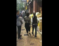 Yellow bird sits on shoulder outside shops