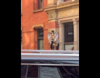 Man wears costume sits on street lamp