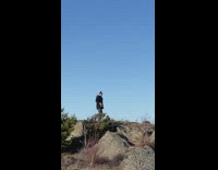 Man black jacket film on rock hill