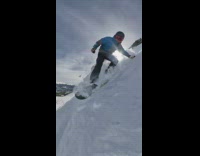 Black helmet guy rides snowboard down mountain 