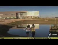 Two girls run into water puddle 