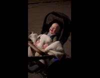 Baby in stroller plays peek-a-boo with blanket