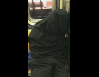 person fully covered in black jacket on subway sleeping