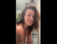 Woman in the shower with pet parrot on shoulder 