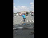Collab WINY - Man in blue red costume rides bike 