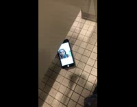 Person slides phone under restroom stall