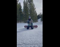 Two people snowboard by camera joking they cant stop