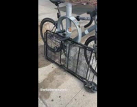 Folded black cart bicycle locked to rack 