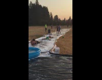Guy green shorts slips on DIY slip and slide outside hits head