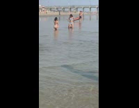 Blue bikini girl kneels beach shore bridge