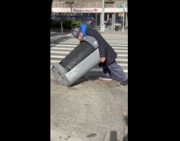 Man lean into tilted trash can street