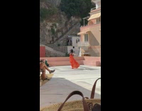 Woman orange dress belly spin dance rooftop 