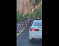 Two girls stand street brown mountain behind 