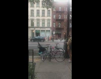 Small orange trex dinosaur walks with girl on sidewalk