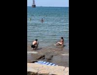 Collab IITW - Woman orange bikini sits on beach rock