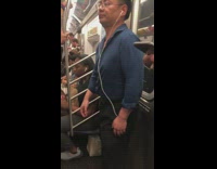 Guy in blue button up shirt earphones moves hips and dances with eyes closed on subway train