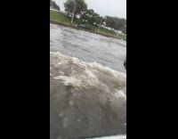 Car drives on flooded highway creates waves 