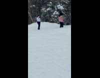 Two women poses beside trees in snow