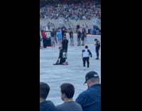 Man kneels spread arms near the concert stage