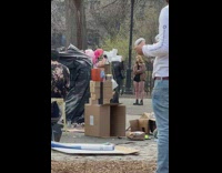 Person in trash bag at art exhibit and another guy using VR at park
