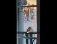 Woman floral jumpsuit dress poses on the balcony barrier