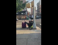 Guy sitting on office chair with leg on suitcase on sidewalk