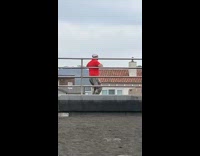 Man red shirt dance beach fence tripod