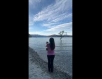 Collab PLC - Woman pink top hold cat stand on lake shore