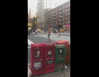 Guy plays the flute while wearing black and white sarong in the middle of the street