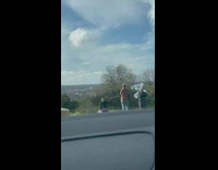 Woman black coat kneel grass silver balloons