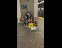 Man plays Old McDonald on blue melodica with dozens of dancing puppet dolls around him