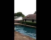 Guy in swim shorts rolls and falls off roof into pool