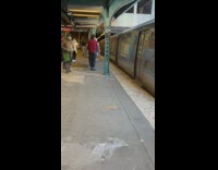 Two people moving new grey couch onto train