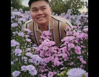 Guy smiles in field purple flowers