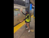 Lady wearing runway controller costume waves subway in  