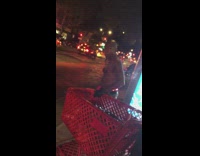 Guy wears light up orange boxers next to red shopping cart on sidewalk