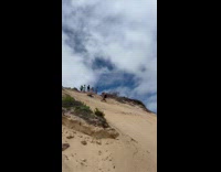 Man Trips While he Runs Downhill on Sandy Slope