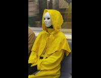 White mask yellow cape costume on subway