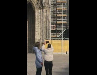 Two Women Take Photo of their Food Plate in Front of Cathedral 