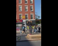 Man blows into conch standing in the middle of the marathon runners