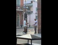 Man with cap poses on sidewalk corner