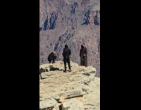 Man in robe poses edge of canyon