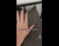 Black kitten hiding behind pillow 