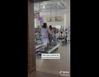 Two people at gym walking on same treadmill together