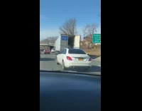 Passenger records the back door of a semitruck swinging open on the freeway
