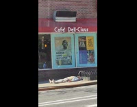 Guy lays on back on sidewalk cafe 