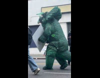 Green triceratops dinosaur mascot walk on street