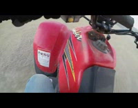 Guy drifts red ATV does donuts 