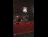 man in red convertible head banging