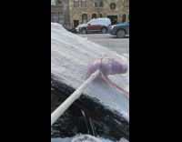 Person uses hobby horse to scrape snow off car